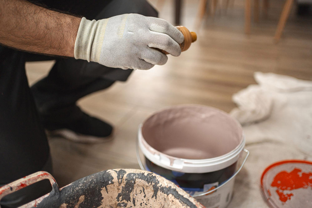 A man painting a room with a bucket of paint.